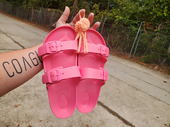 Hot pink slides hanging off my pastel orange Shower Sandal Holder.