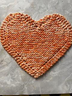 full image of a heart-shaped dishcloth in orange and white variegated cotton blended yarn.
