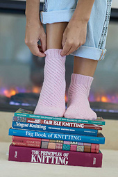 Image Description: someone wearing a pair of socks that spiral in a tight cable pattern