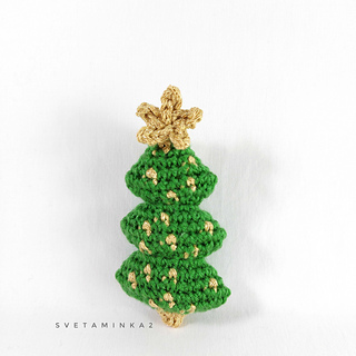 A crocheted bright green festive tree with an imitation of golden garlands and 'star', made from a detailed crochet christmas pattern.