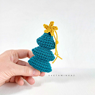 An elegantly shaped Christmas tree amigurumi in traditional colors, made from a detailed crochet pattern.