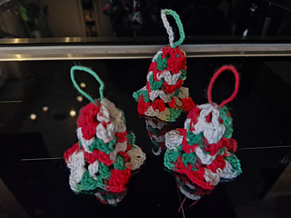 Three crocheted Christmas bell and tree ornaments in red, green and white with loops for hanging